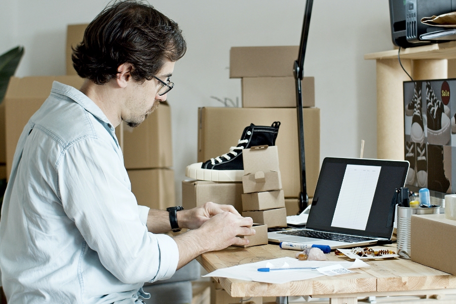 man with laptop and boxed representing a direct to consumer approach
