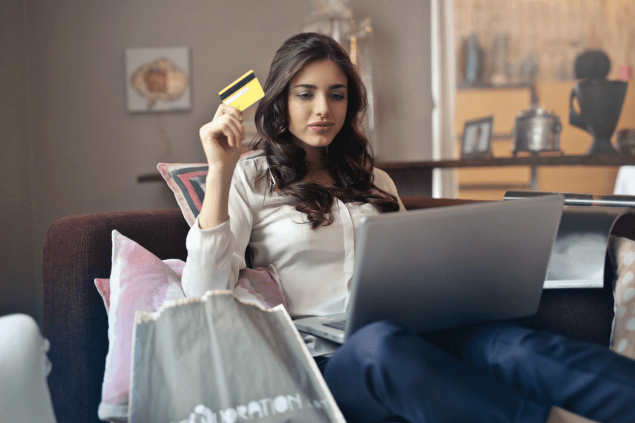 lady holding a credit card in front of a laptop